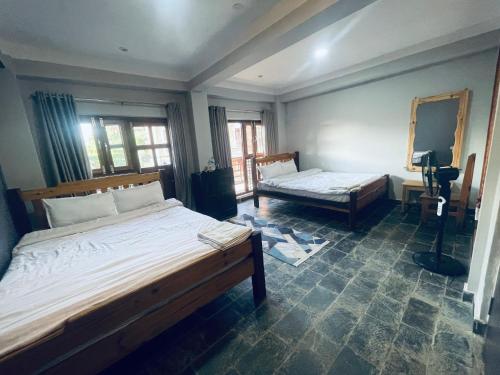 a bedroom with two beds and a mirror at Pasne Aajako Hotel in Bandipur