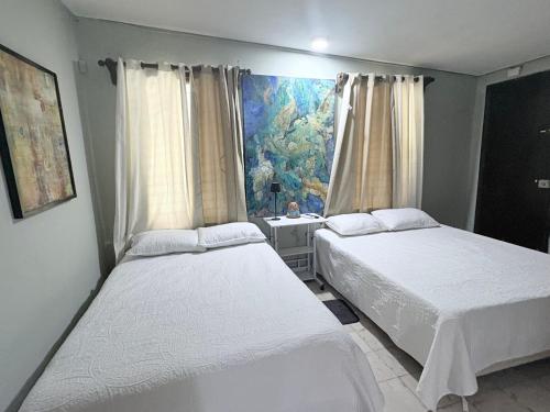 a bedroom with two beds and a window with a fish mural at Casa Buenavista in Mérida