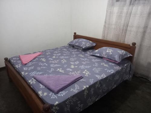a bed with purple and pink pillows on it at Sahan tours in Padukka