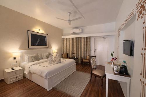 a bedroom with a large white bed and a television at Sanskriti Vedic Retreat in Rishīkesh