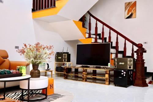a living room with a television and a staircase at Mocha Vila Mộc Châu in Mộc Châu