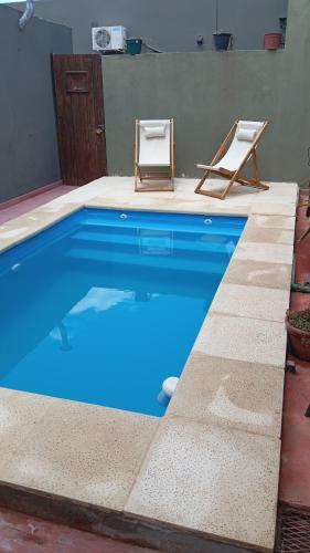a blue swimming pool with two chairs and a table at Excepcional Centro Chascomus in Chascomús