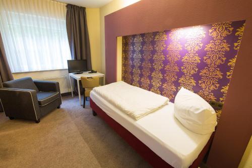 a hotel room with a bed and a chair at BSW Ferienhotel Lindenbach in Bad Ems