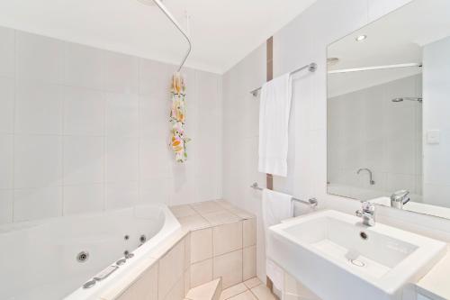een witte badkamer met een bad en een wastafel bij Beach Resort Apartment in Port Macquarie