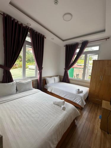 two beds in a room with two windows at Khách sạn Hoa Chuông, trung tâm Đà Lạt in Da Lat