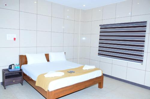 a white bedroom with a bed and a window at ARS INN AND MINI HALL Vellore in Vellore