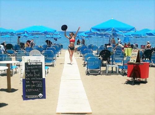 a woman is walking down a path on the beach at Frank Apartments in Amoudara Herakliou