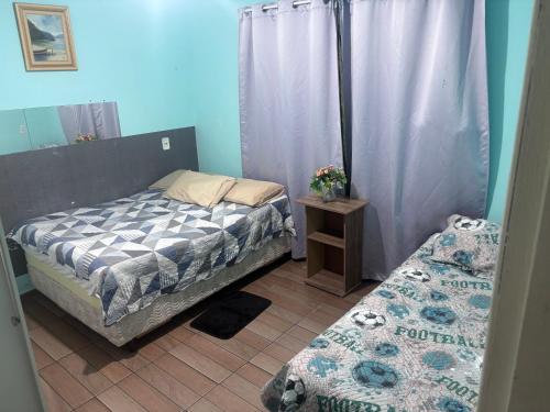 a bedroom with two twin beds and a table with a bedskirts at Praia do sonho, Quarto para até 4 pessoas super aconchegante in Palhoça