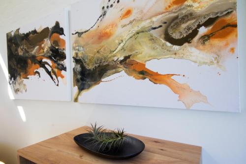 two paintings on a wall with a plant on a table at THEBLOEM Guest Suites by Knysna Paradise Collection in Knysna