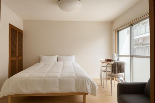 a bedroom with a bed and a chair and a window at 旅館ほのか in Osaka