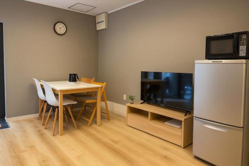 a kitchen with a table and a refrigerator and a table and chairs at 旅館ほのか in Osaka