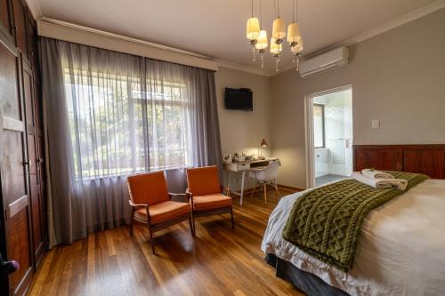 a bedroom with a bed and two chairs and a table at Archers Guest House in Patentie