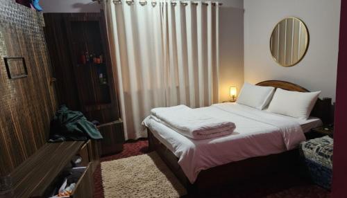 a bedroom with a bed with white sheets and a mirror at Hotel Rani mahal Biratnagar in Biratnagar