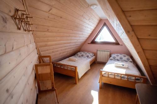 a attic room with two beds and a window at Pod Tatrami widok na Tatry, sauna, parking, blisko Term Bukovina in Bukowina Tatrzańska