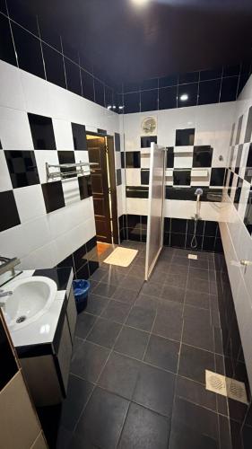 a black and white bathroom with a sink and a shower at The Bala's Holiday Chalet in Cameron Highlands