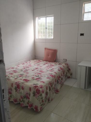 a small bedroom with a bed with a flowered blanket at 3-bedroom house on Cabuçu beach in Saubara