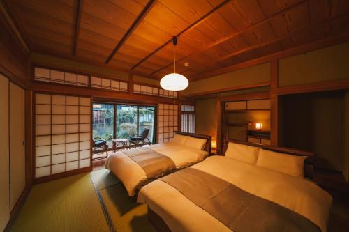 a bedroom with two beds and a pendant light at アリュール照波園 in Beppu