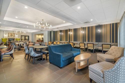 a restaurant with tables and chairs and a blue couch at The Clocktower Hotel Latham - North Albany, an Ascend Collection Hotel in Cohoes