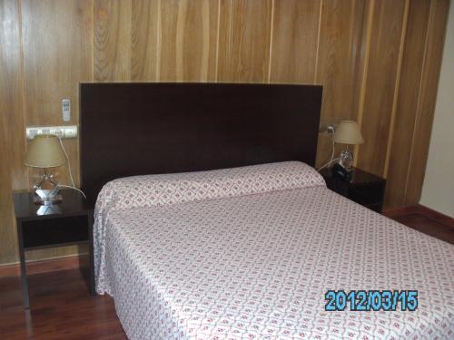 a bedroom with a bed and two night stands with lamps at Hotel La Duquesa in Pinos Genil