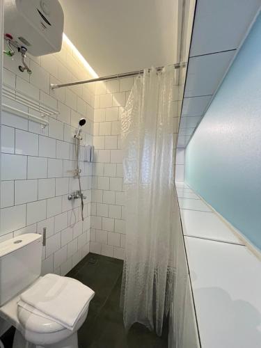a white bathroom with a toilet and a shower at Turuku in Bandung