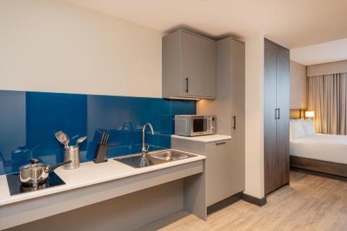 a kitchen with a sink and a microwave at Hyatt House Aparthotel Leeds in Leeds