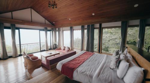 a bedroom with a large bed and a room with windows at amã Stays & Trails Eagle's Nest, Gangtok, Sikkim in Bhurtuk