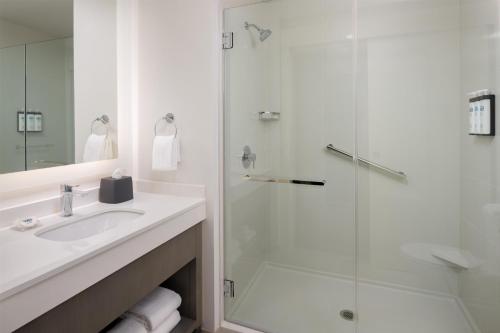 a white bathroom with a shower and a sink at Hyatt House Fresno/Campus Pointe in Fresno