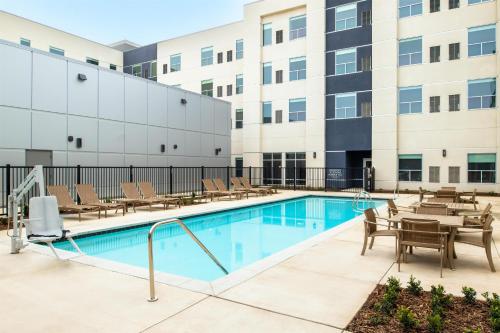 a pool with chairs and tables in front of a building at Hyatt House Fresno/Campus Pointe in Fresno