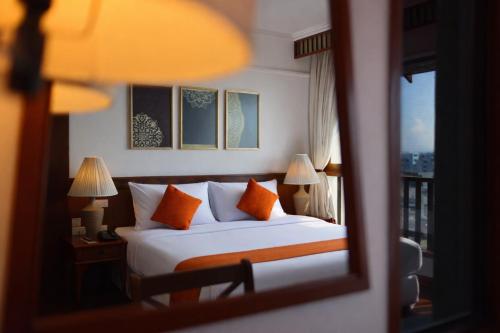 a bedroom with a bed with orange pillows and a window at Wienglakor Hotel Lampang in Lampang