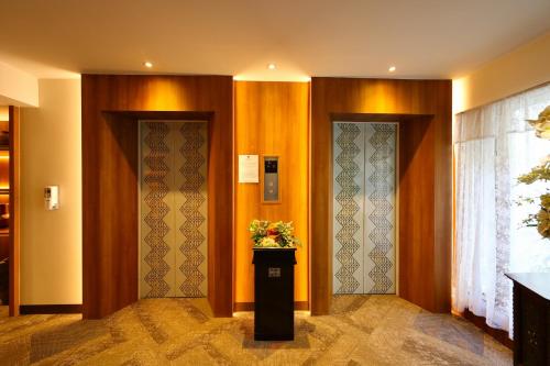 a hallway with two doors and a vase of flowers at Wienglakor Hotel Lampang in Lampang