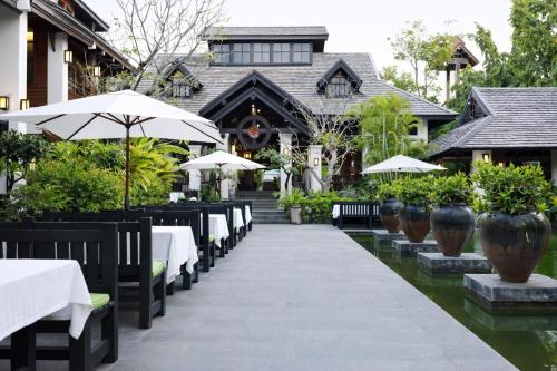 a restaurant with tables and umbrellas in front of a building at Wienglakor Hotel Lampang in Lampang