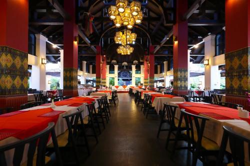a dining hall with tables and chairs and a chandelier at Wienglakor Hotel Lampang in Lampang