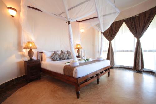 a bedroom with a canopy bed with two lamps at Ocean Paradise Resort & Spa in Pwani Mchangani
