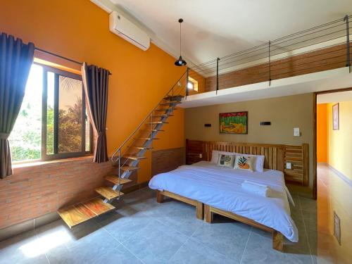 a bedroom with a bed and a spiral staircase at Orange Villa Muine in Mui Ne