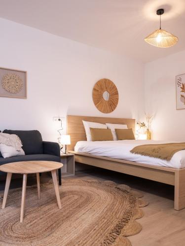 a bedroom with a bed and a couch and a table at Studio chic proche aéroport et centre-ville in Charleroi