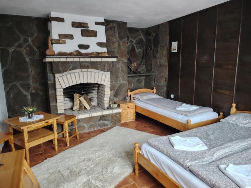 a room with two beds and a fireplace at Къща за гости Бащин дом in Apriltsi
