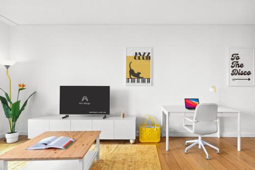 a white living room with a tv and a desk at Central luminous 2 beds with balcony & aircon in Sydney
