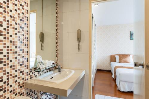 a bathroom with a sink and a bed in a room at Summit Pavilion Hotel in Bangkok