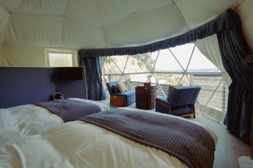 a bedroom with a bed and two chairs and a window at Shinon 森音 in Tateyama