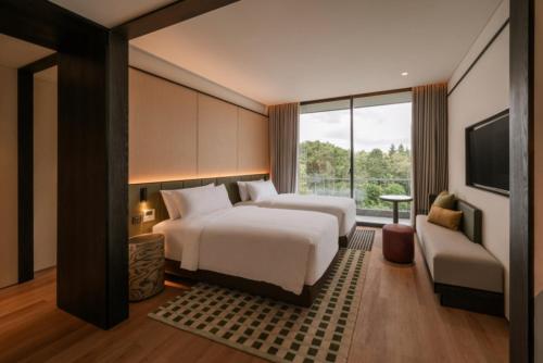 a hotel room with two beds and a tv at Nawana Sentul City by Alana in Bogor