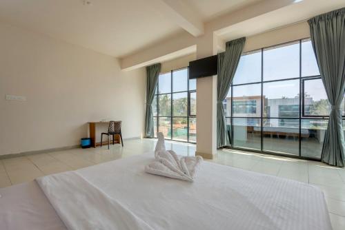 a bedroom with a white bed with a large window at Grape Rooms in Perintalmanna