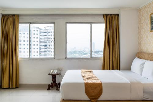 a hotel room with a bed and two windows at Summit Pavilion Hotel in Bangkok