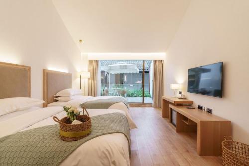 a hotel room with two beds and a flat screen tv at Xianzai Houshe Boutique Hotel in Dujiangyan