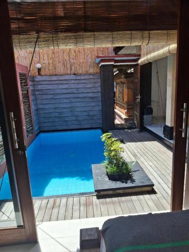 a large blue swimming pool with a plant on a patio at Jukung Villas Kuta in Kuta