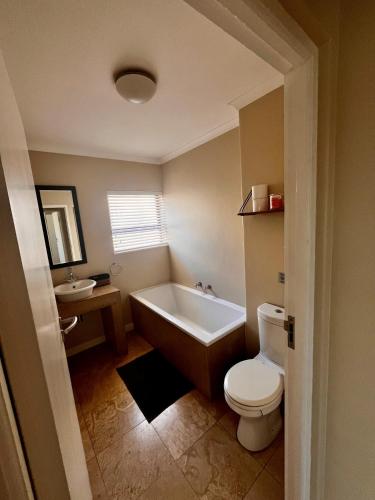 a bathroom with a tub and a toilet and a sink at Hill Fore! in Langebaan