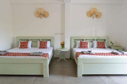 two beds sitting in a room with at Mira Mirissa in Mirissa