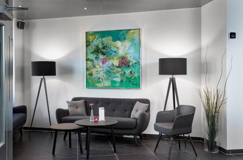 a living room with a couch and a table and a painting at Hotel Cabinn Vejle in Vejle