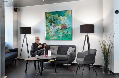un hombre sentado en un sofá en una sala de estar en Hotel Cabinn Vejle en Vejle