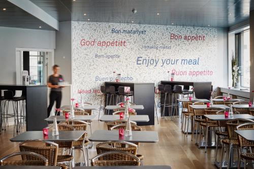 a man standing in a restaurant with tables and chairs at Hotel Cabinn Vejle in Vejle