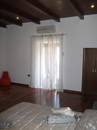 a bedroom with a bed and a window with white curtains at Dimora di Mara in Santeramo in Colle